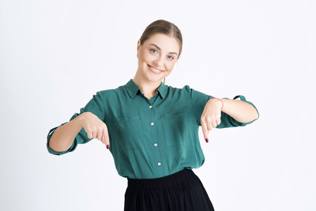 A young woman points her fingers down at an empty copy space for advertising, isolated on a white studio background. Advertising: Partnering with Gardner Electrical for Your Indoor & Outdoor Lighting Installation Needs.