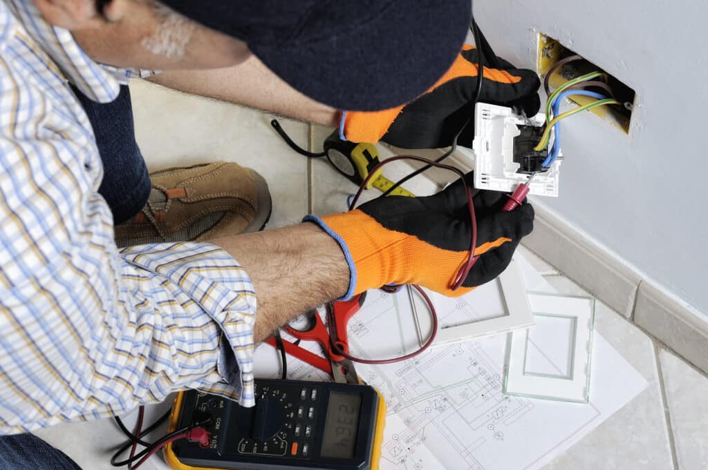 An electrician is measuring the voltage on switches and sockets in a residential electrical system, including checking for reverse polarity.